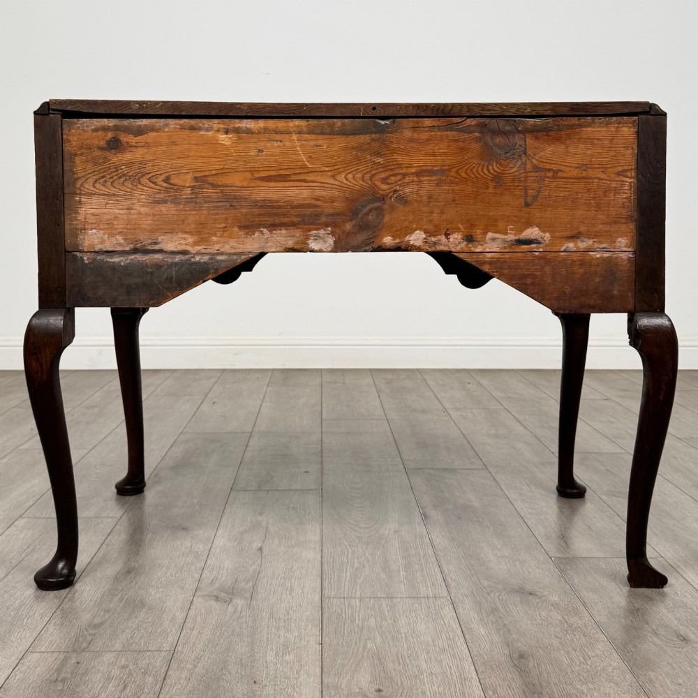 An 18th-century Georgian oak side table featuring three drawers with brass drop handles, an arched apron, and cabriole legs. View V