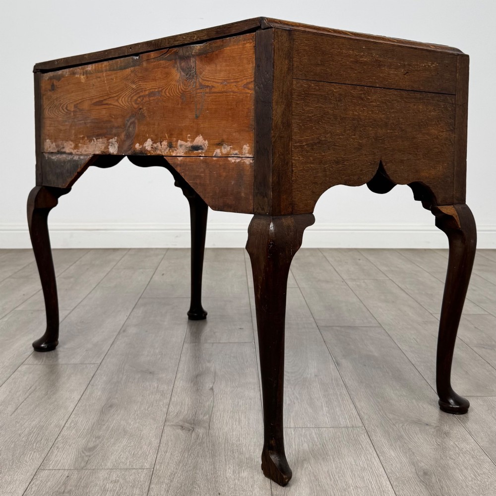 An 18th-century Georgian oak side table featuring three drawers with brass drop handles, an arched apron, and cabriole legs. View VI