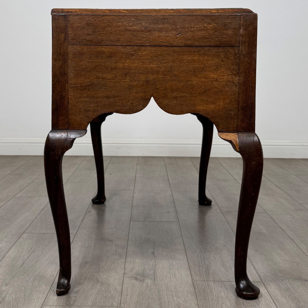 An 18th-century Georgian oak side table featuring three drawers with brass drop handles, an arched apron, and cabriole legs. View VII