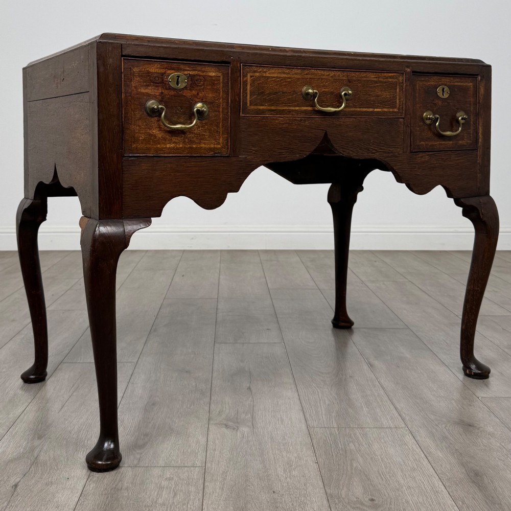 An 18th-century Georgian oak side table featuring three drawers with brass drop handles, an arched apron, and cabriole legs. View VIII