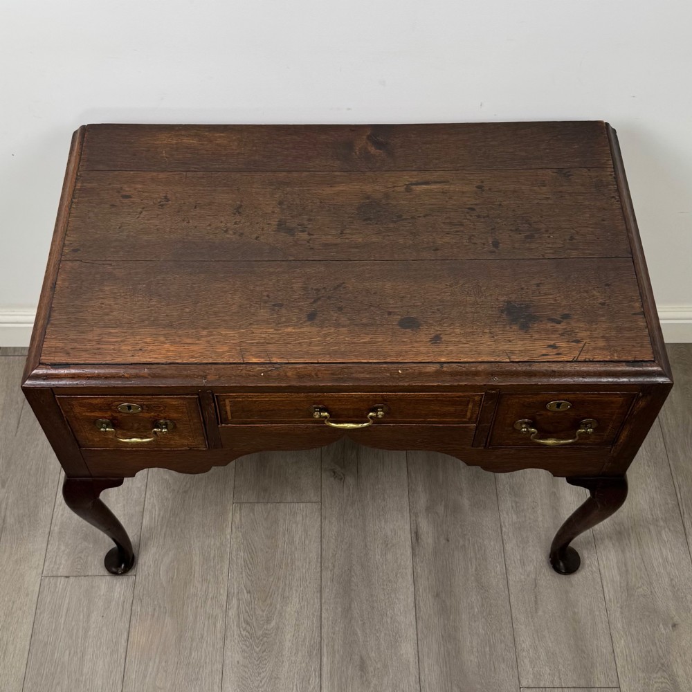 An 18th-century Georgian oak side table featuring three drawers with brass drop handles, an arched apron, and cabriole legs. View IX