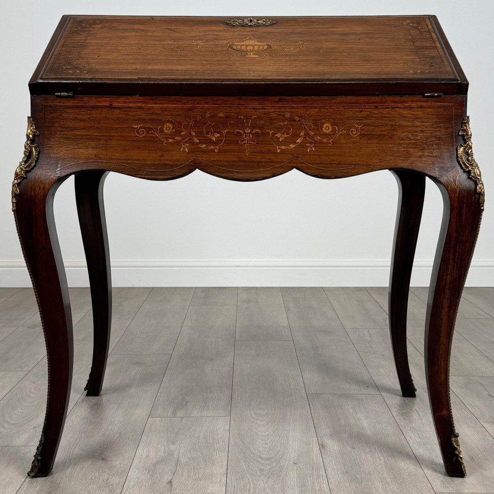 A 19th-century French rosewood bureau de dame with floral marquetry inlay on the hinged top and apron, raised on cabriole legs with gilt-bronze ormolu mounts.