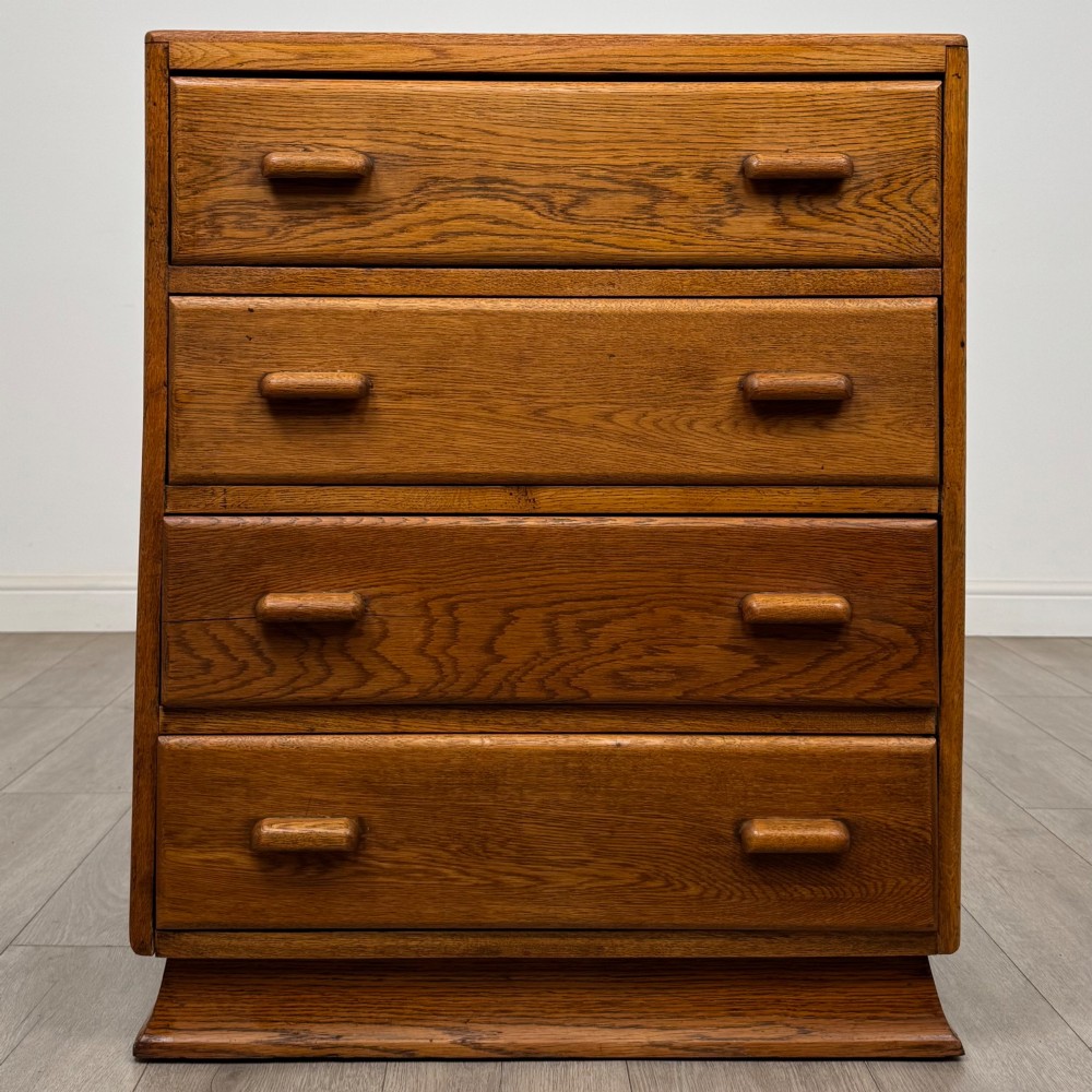 A vintage medium-toned oak chest of drawers featuring four graduated drawers with matching wooden bar handles set on a flared plinth base.