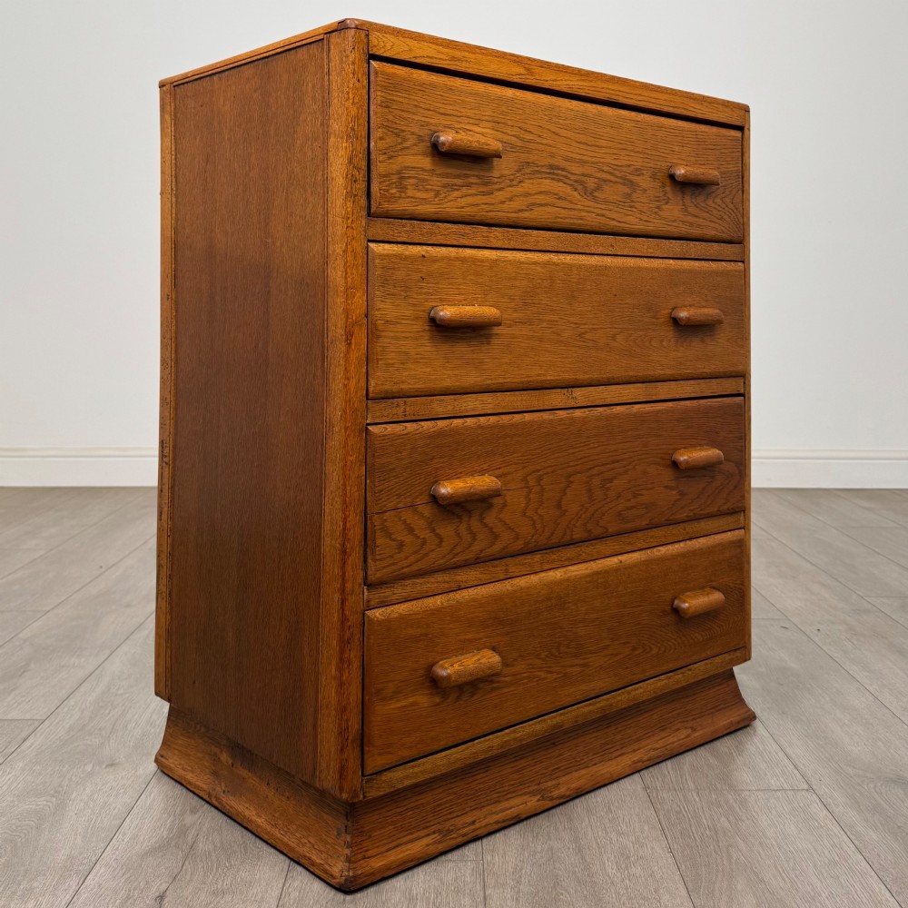 A vintage medium-toned oak chest of drawers featuring four graduated drawers with matching wooden bar handles set on a flared plinth base. View VIII