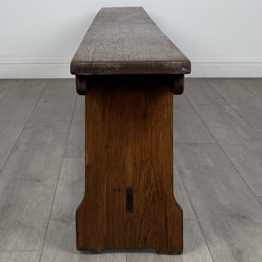 A long 19th-century Georgian oak tavern bench featuring a smooth plank seat supported by three sturdy slab legs and a full-length lower stretcher. View VII
