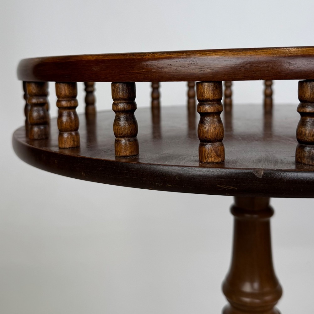 A dark brown beech side table featuring a spindle gallery rim around the circular top, a turned column support, and a tripod base with claw feet. View VII