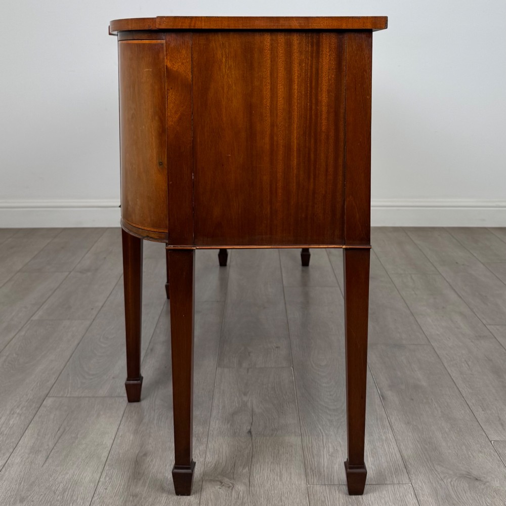 A 19th-century mahogany bow-front sideboard with central drawers, side cupboards, and tapered square legs. View IV