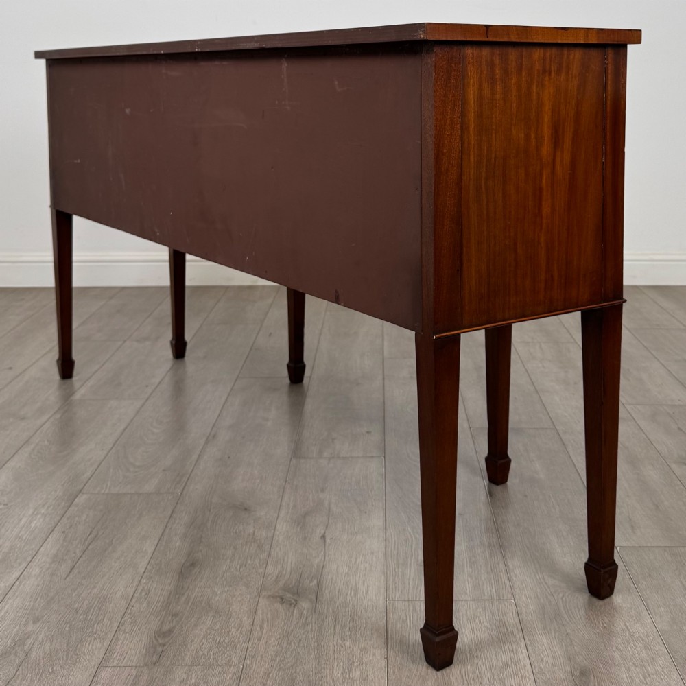 A 19th-century mahogany bow-front sideboard with central drawers, side cupboards, and tapered square legs. View VII