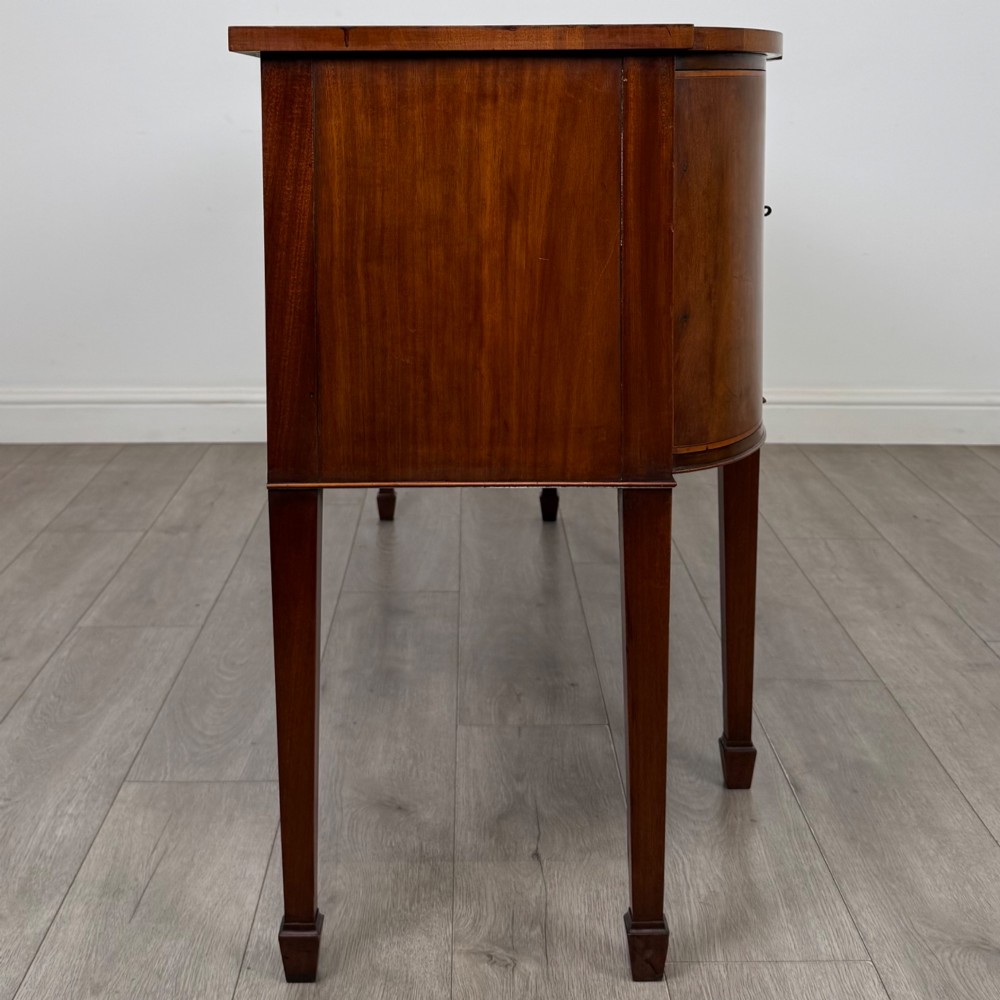 A 19th-century mahogany bow-front sideboard with central drawers, side cupboards, and tapered square legs. View VIII
