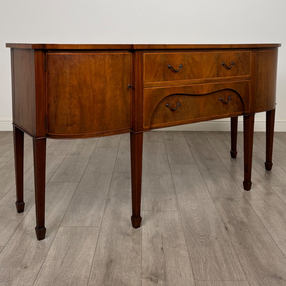 A 19th-century mahogany bow-front sideboard with central drawers, side cupboards, and tapered square legs. View IX