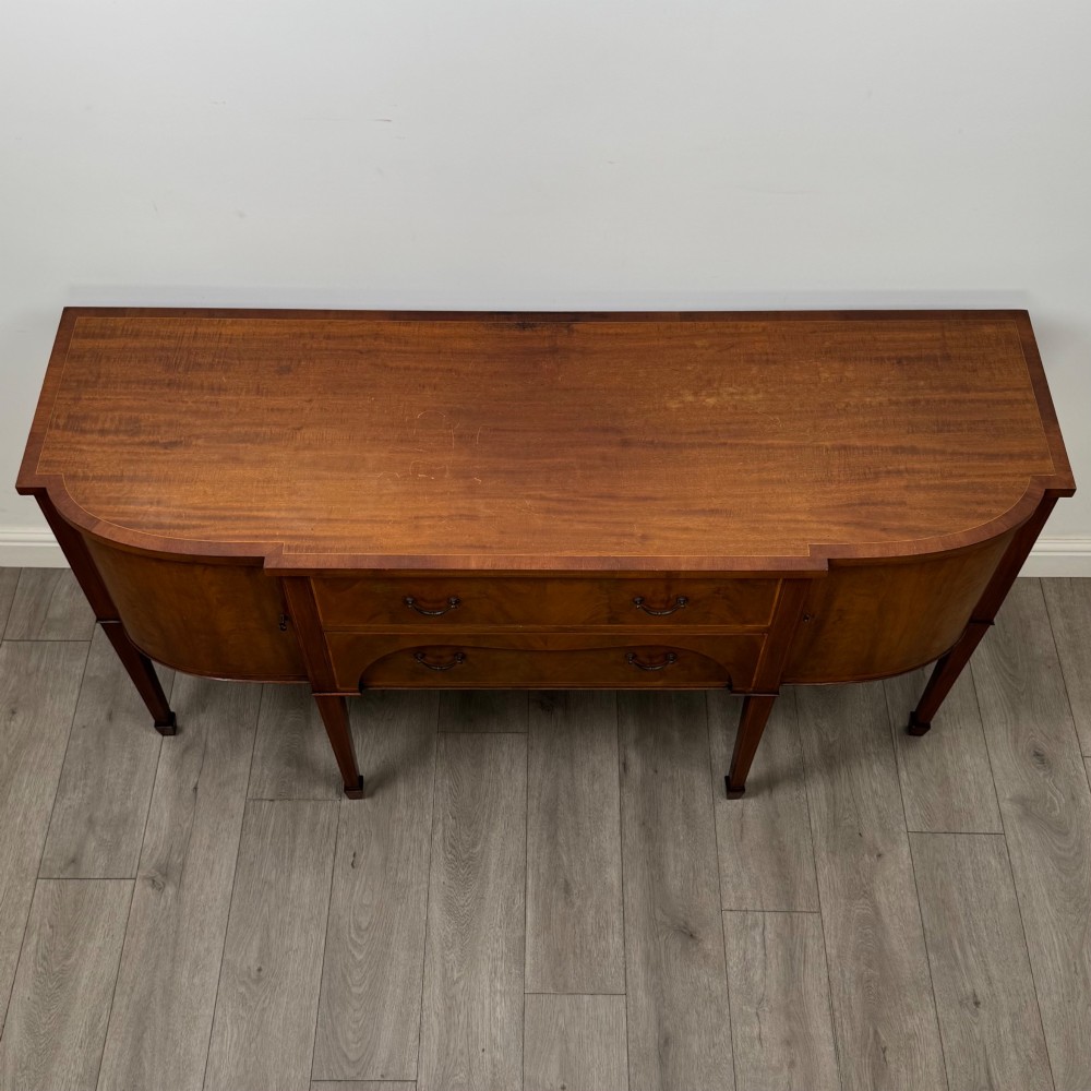 A 19th-century mahogany bow-front sideboard with central drawers, side cupboards, and tapered square legs. View X