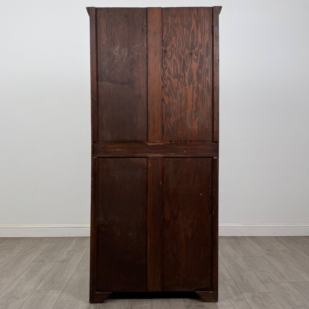 A tall single-door dark oak Edwardian wardrobe featuring a carved upper linenfold panel and decorative iron hinges. View VI