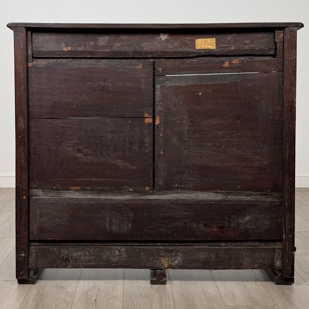 A 19th-century dark oak open bookcase featuring hand-carved frieze foliage, a central mask motif, and three tiers of open shelving. View V