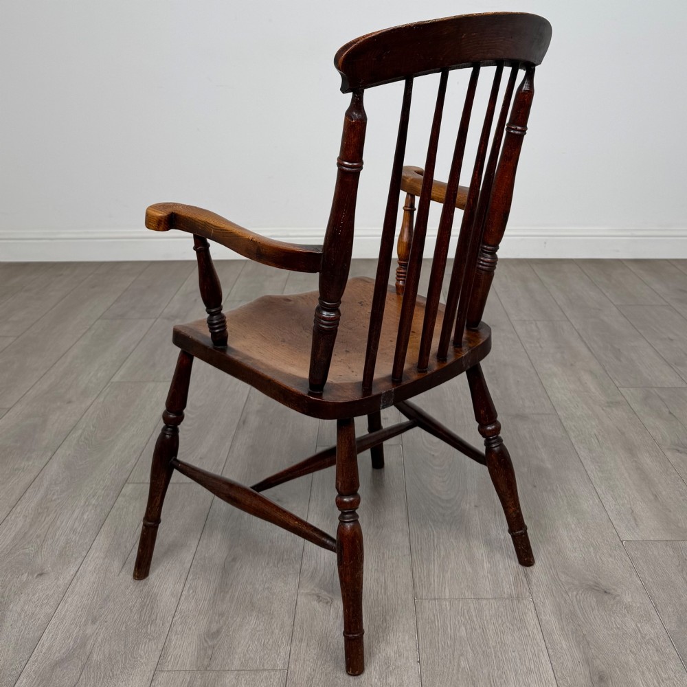 An antique 19th-century oak stick back armchair featuring turned spindle backrests, curved wooden armrests, a contoured solid seat, and turned legs joined by stretchers. View III