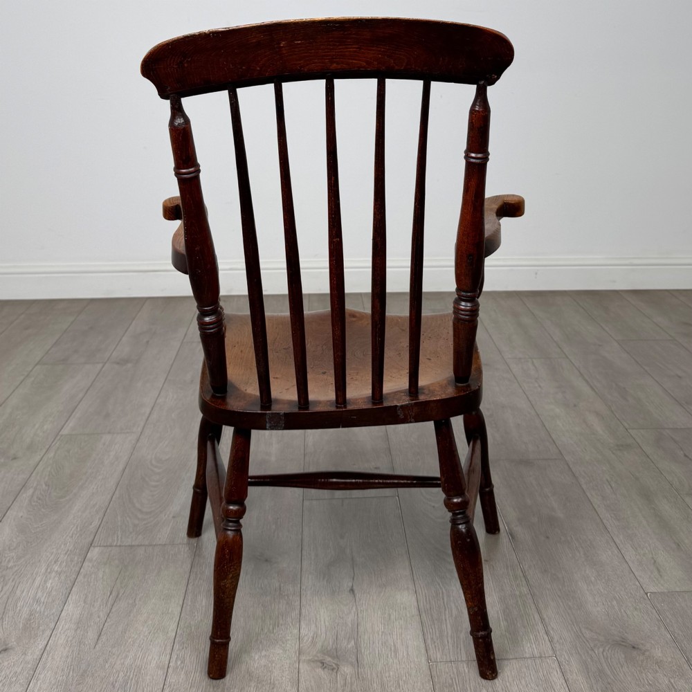 An antique 19th-century oak stick back armchair featuring turned spindle backrests, curved wooden armrests, a contoured solid seat, and turned legs joined by stretchers. View IV