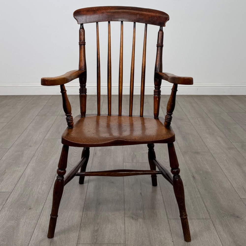 An antique 19th-century oak stick back armchair featuring turned spindle backrests, curved wooden armrests, a contoured solid seat, and turned legs joined by stretchers. View VIII