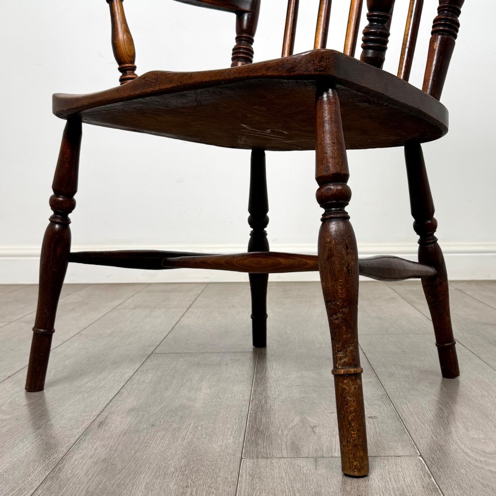 An antique 19th-century oak stick back armchair featuring turned spindle backrests, curved wooden armrests, a contoured solid seat, and turned legs joined by stretchers. View XI