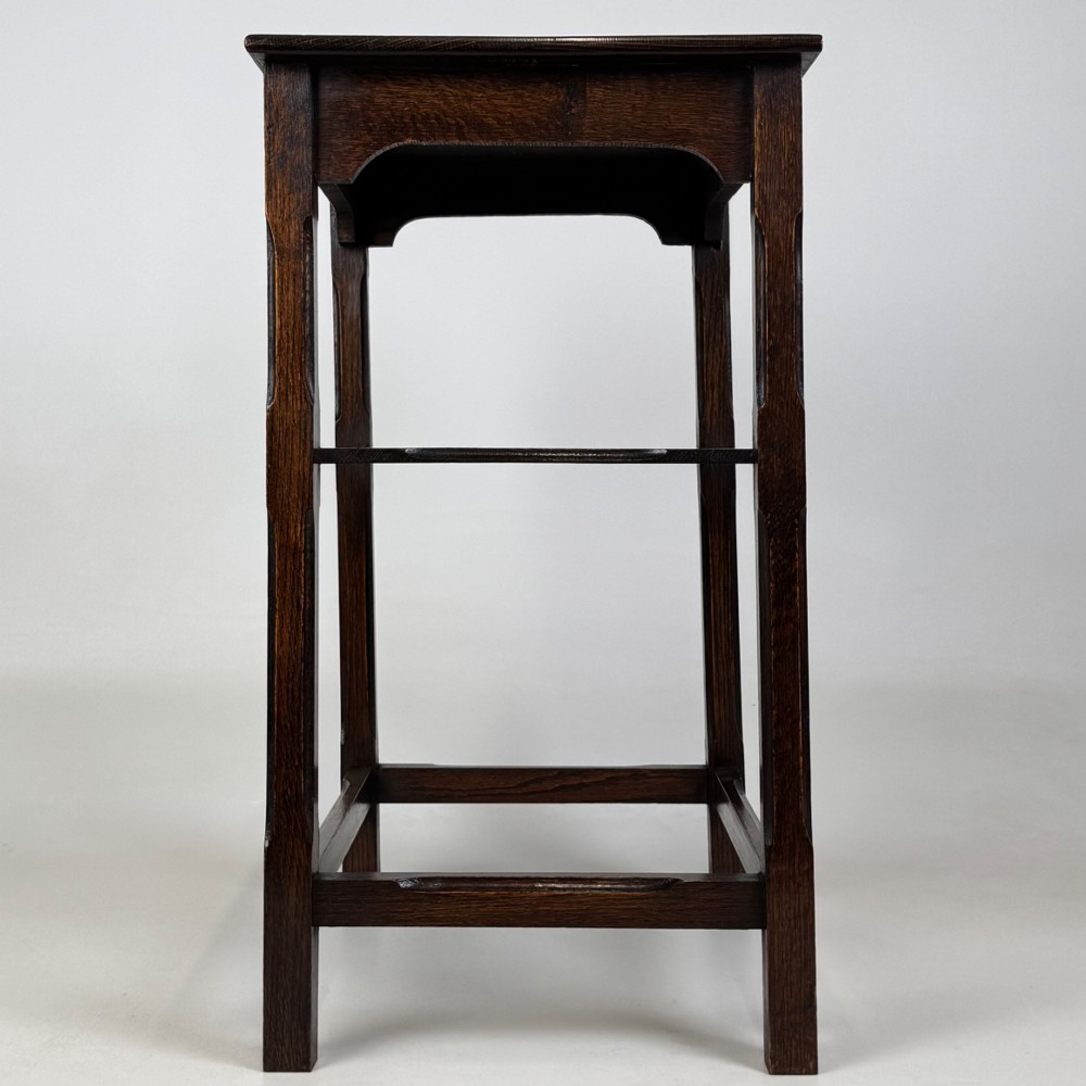 An Edwardian dark oak side table with a flat square top, lower tier shelf, shaped aprons, and straight square legs. View VII