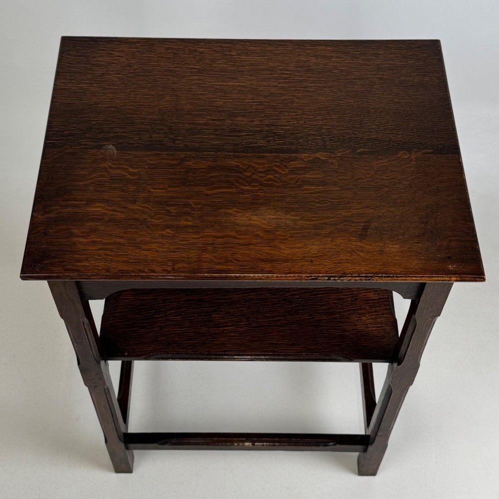An Edwardian dark oak side table with a flat square top, lower tier shelf, shaped aprons, and straight square legs. View IX