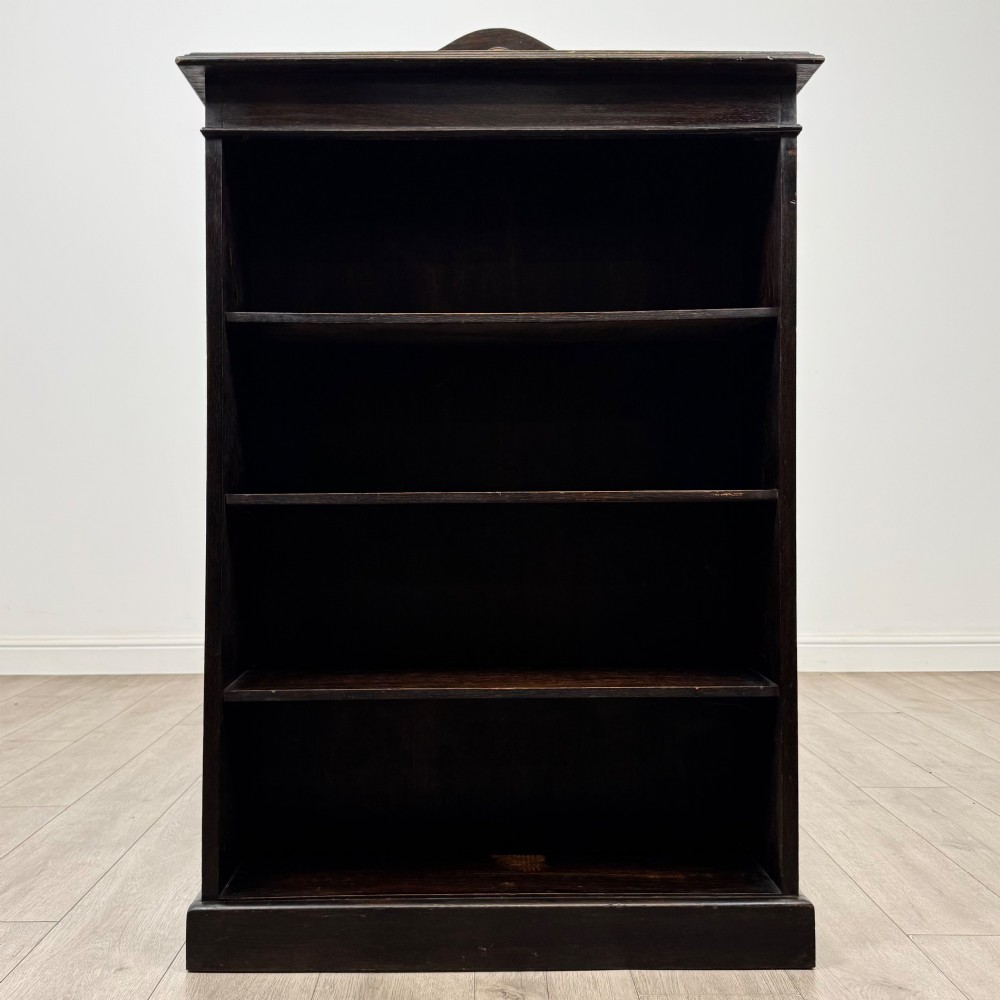 An Edwardian dark-stained oak open bookcase featuring four shelf tiers containing red leather-bound books against a white background. View II