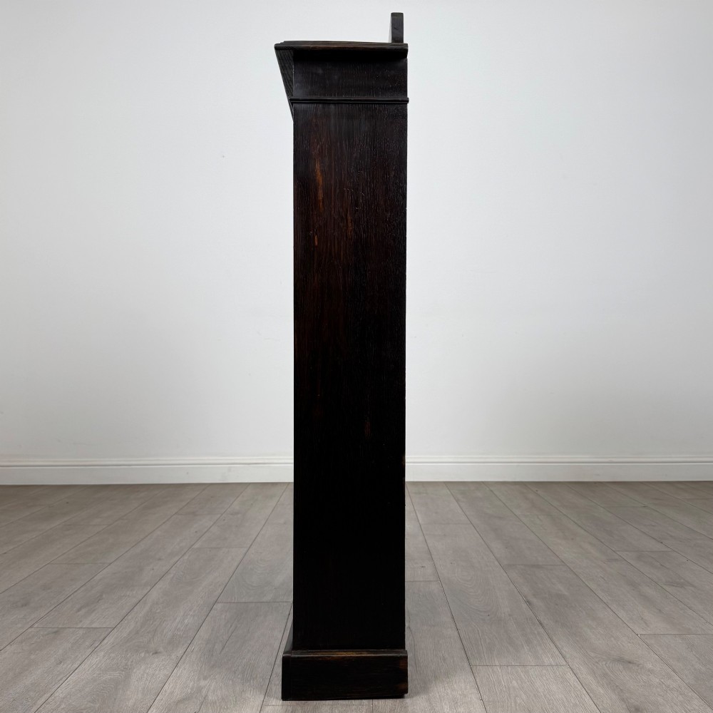 An Edwardian dark-stained oak open bookcase featuring four shelf tiers containing red leather-bound books against a white background. View IV