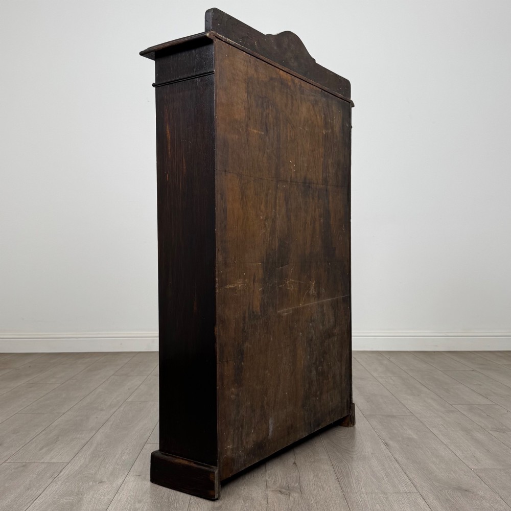 An Edwardian dark-stained oak open bookcase featuring four shelf tiers containing red leather-bound books against a white background. View V