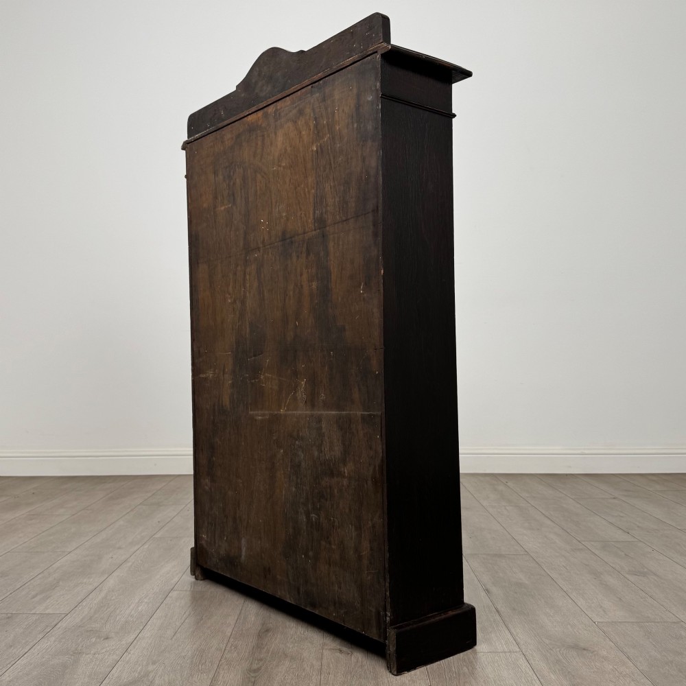 An Edwardian dark-stained oak open bookcase featuring four shelf tiers containing red leather-bound books against a white background. View VII