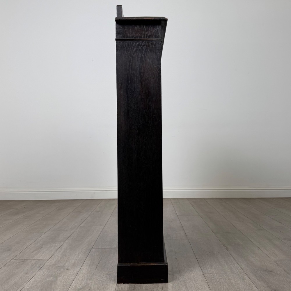 An Edwardian dark-stained oak open bookcase featuring four shelf tiers containing red leather-bound books against a white background. View VIII