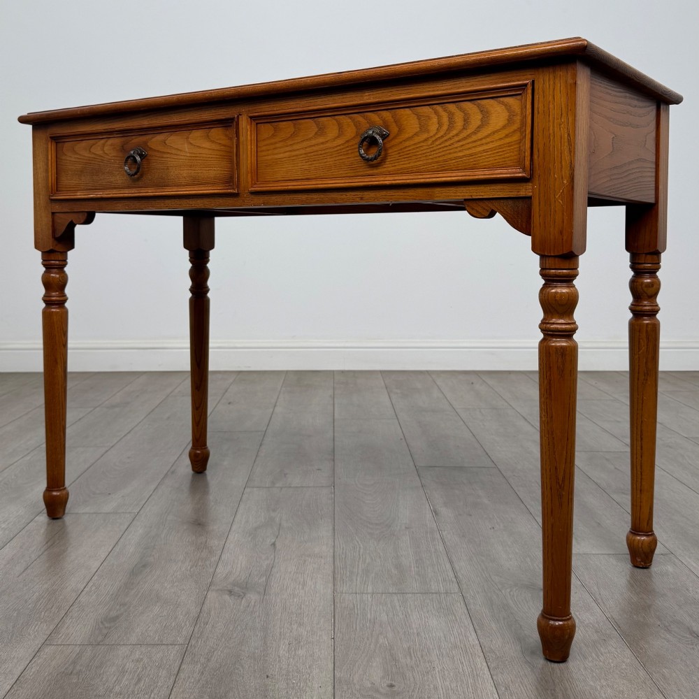 A 20th-century warm brown oak writing table featuring two frieze drawers with ring drop handles and four turned legs. View II