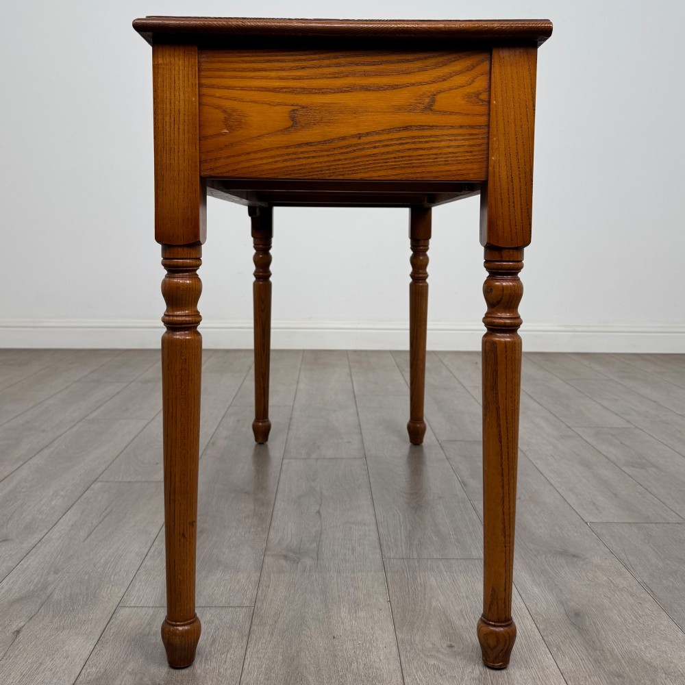A 20th-century warm brown oak writing table featuring two frieze drawers with ring drop handles and four turned legs. View III