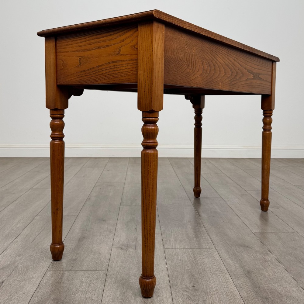 A 20th-century warm brown oak writing table featuring two frieze drawers with ring drop handles and four turned legs. View IV