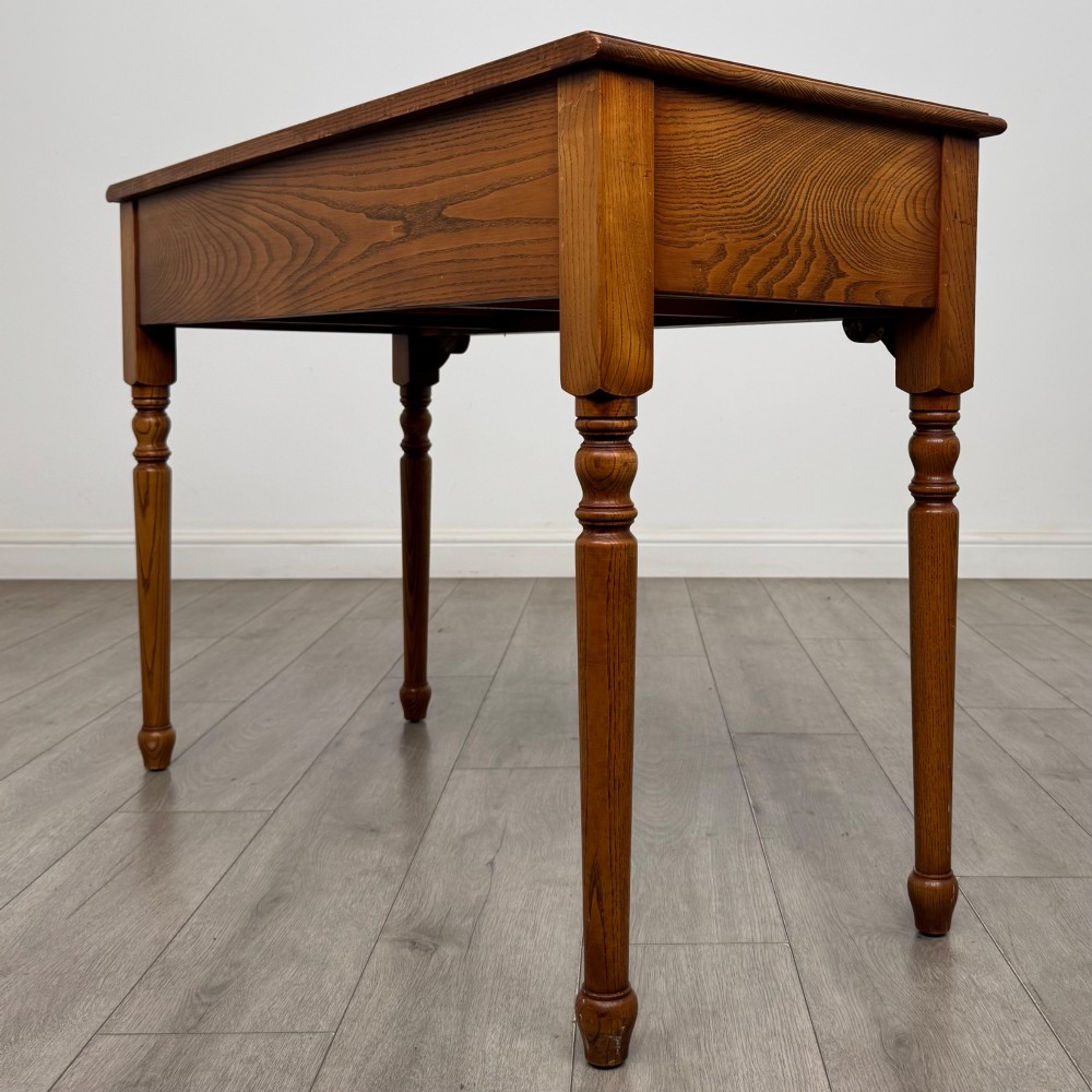 A 20th-century warm brown oak writing table featuring two frieze drawers with ring drop handles and four turned legs. View VI