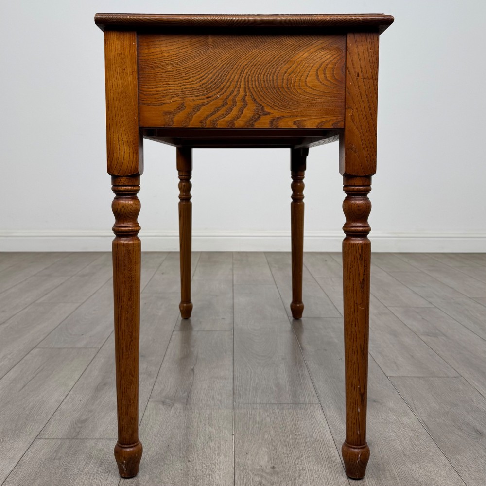 A 20th-century warm brown oak writing table featuring two frieze drawers with ring drop handles and four turned legs. View VII