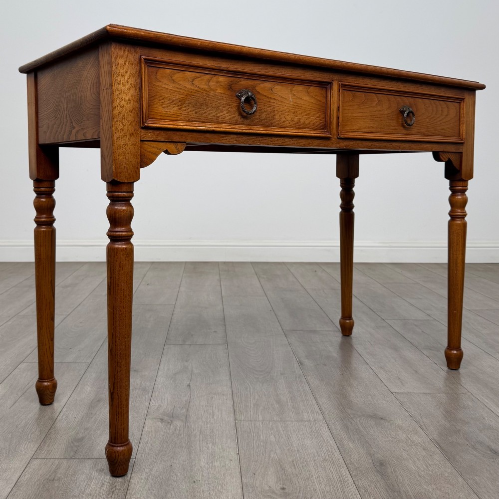 A 20th-century warm brown oak writing table featuring two frieze drawers with ring drop handles and four turned legs. View VIII
