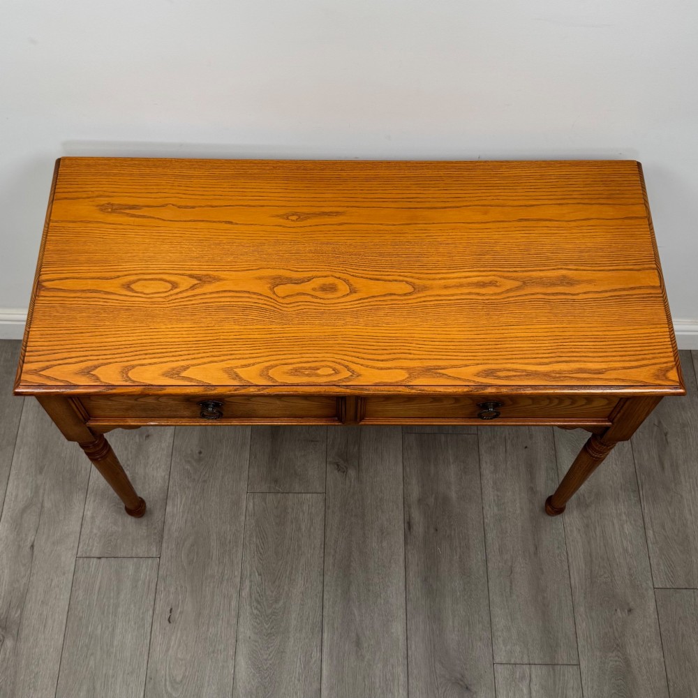 A 20th-century warm brown oak writing table featuring two frieze drawers with ring drop handles and four turned legs. View IX