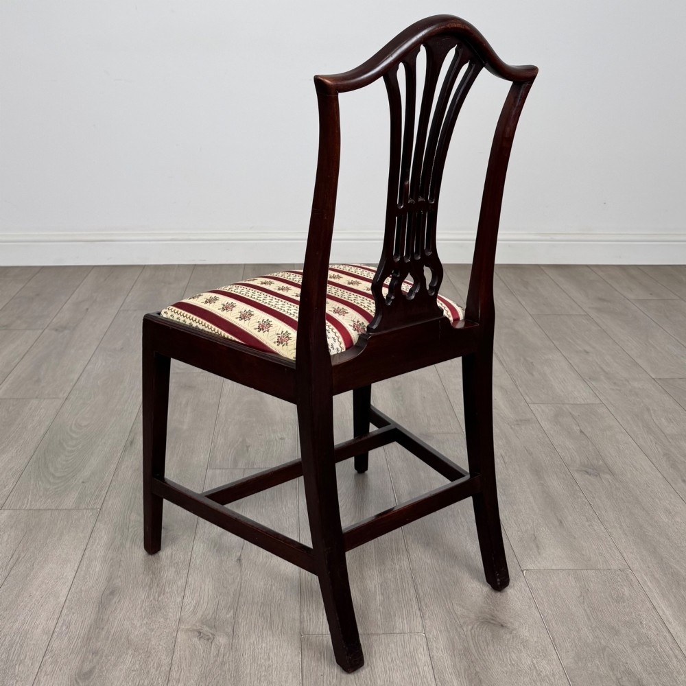 A set of eight dark mahogany shield back dining chairs, including two carvers and six side chairs, with striped red and cream upholstery. View IV