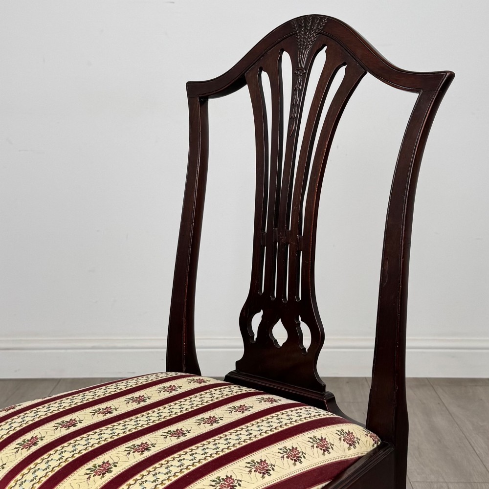 A set of eight dark mahogany shield back dining chairs, including two carvers and six side chairs, with striped red and cream upholstery. View V
