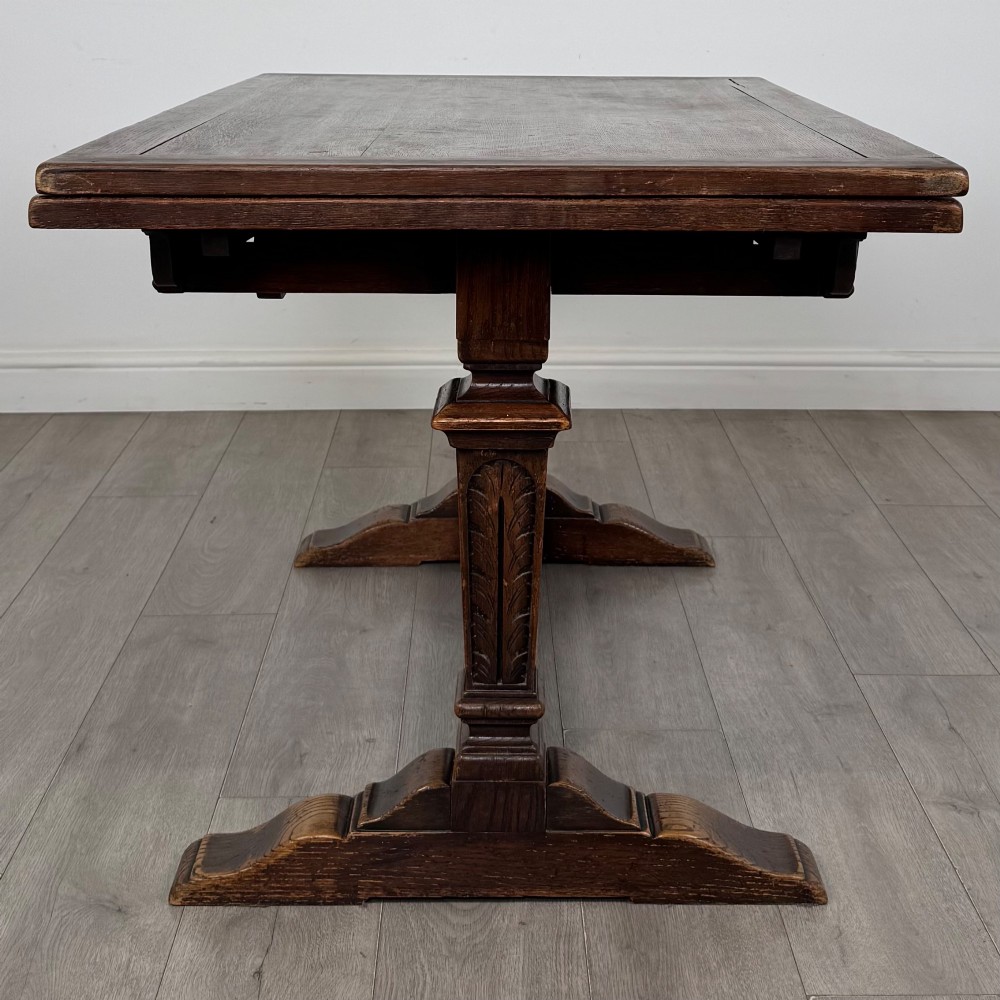 An Edwardian dark oak draw leaf dining table featuring extended side leaves, carved pedestal supports, and a low connecting stretcher. View IV