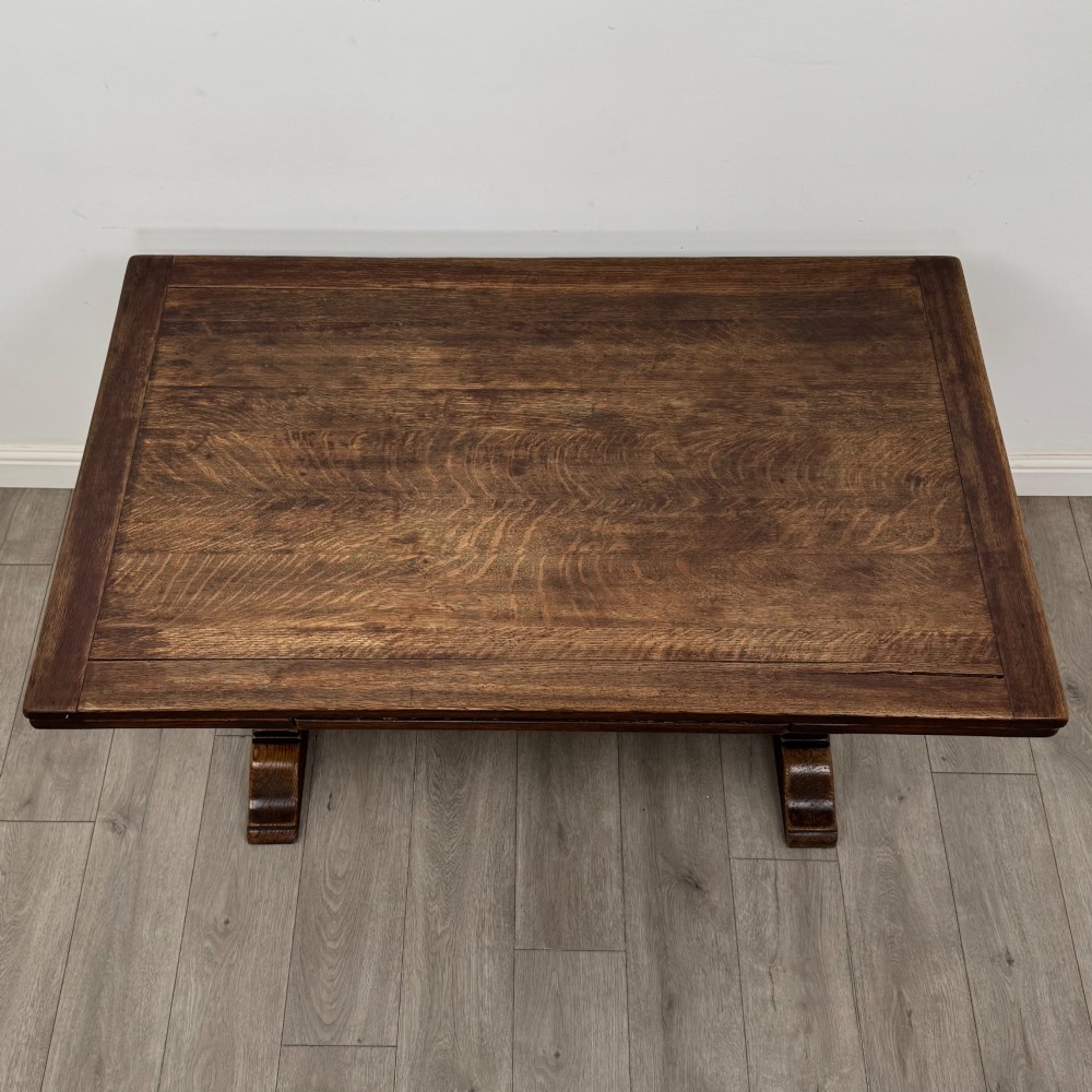 An Edwardian dark oak draw leaf dining table featuring extended side leaves, carved pedestal supports, and a low connecting stretcher. View V