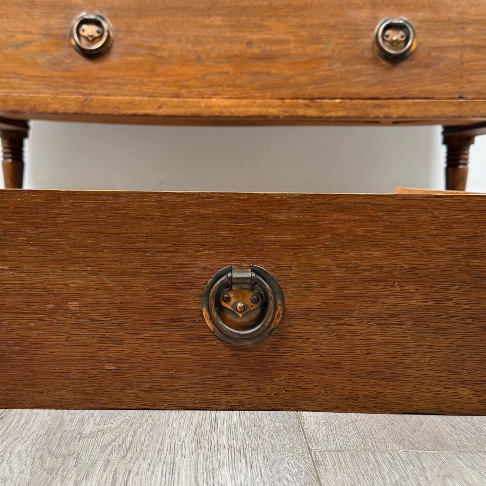An antique Edwardian oak chest featuring three full-width drawers with brass ring drop handles, set on turned legs with castors. View XI