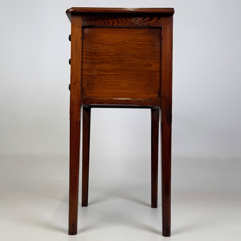A Victorian pitch pine cabinet with three drawers and black wooden knobs set on elevated tapered square legs. View III