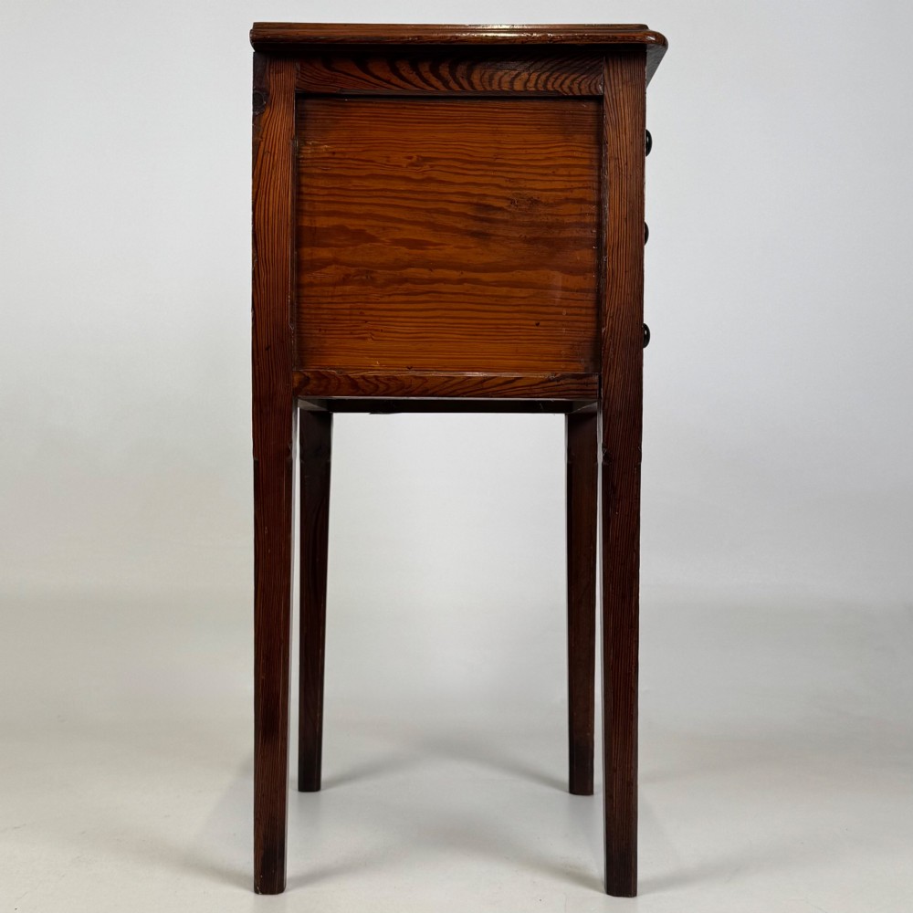 A Victorian pitch pine cabinet with three drawers and black wooden knobs set on elevated tapered square legs. View VII