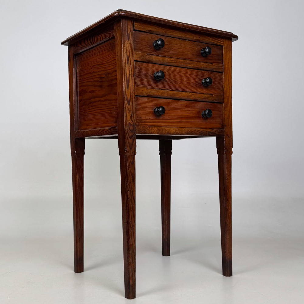 A Victorian pitch pine cabinet with three drawers and black wooden knobs set on elevated tapered square legs. View VIII