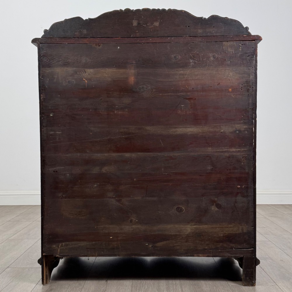 A dark oak Victorian slant-front bureau featuring carved Green Man drawer pulls, foliage relief carvings, and a single panelled cupboard door. View VI
