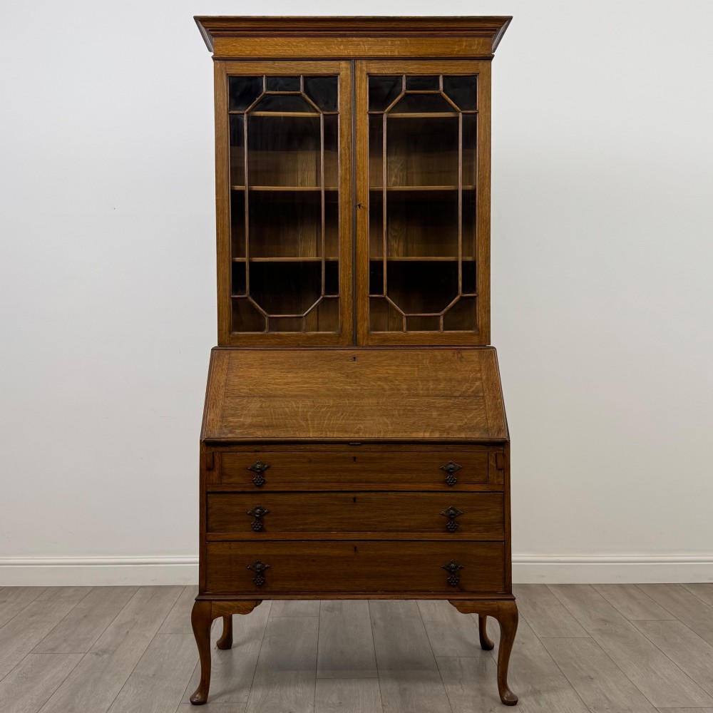 An Edwardian oak bureau bookcase with a two-door upper glazed display cabinet, a sloping drop-front desk, three wide drawers, and cabriole legs. View II