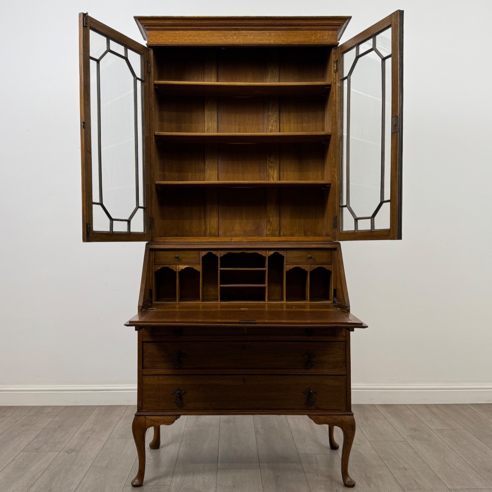 An Edwardian oak bureau bookcase with a two-door upper glazed display cabinet, a sloping drop-front desk, three wide drawers, and cabriole legs. View III