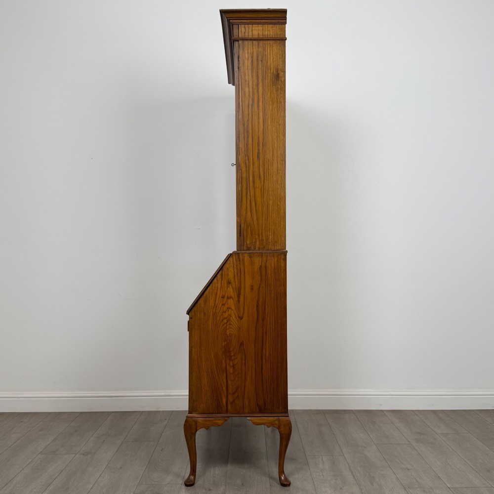 An Edwardian oak bureau bookcase with a two-door upper glazed display cabinet, a sloping drop-front desk, three wide drawers, and cabriole legs. View V