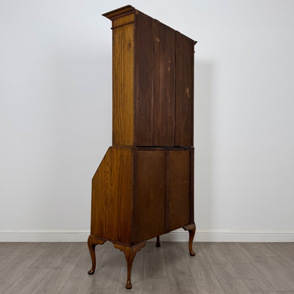 An Edwardian oak bureau bookcase with a two-door upper glazed display cabinet, a sloping drop-front desk, three wide drawers, and cabriole legs. View VI