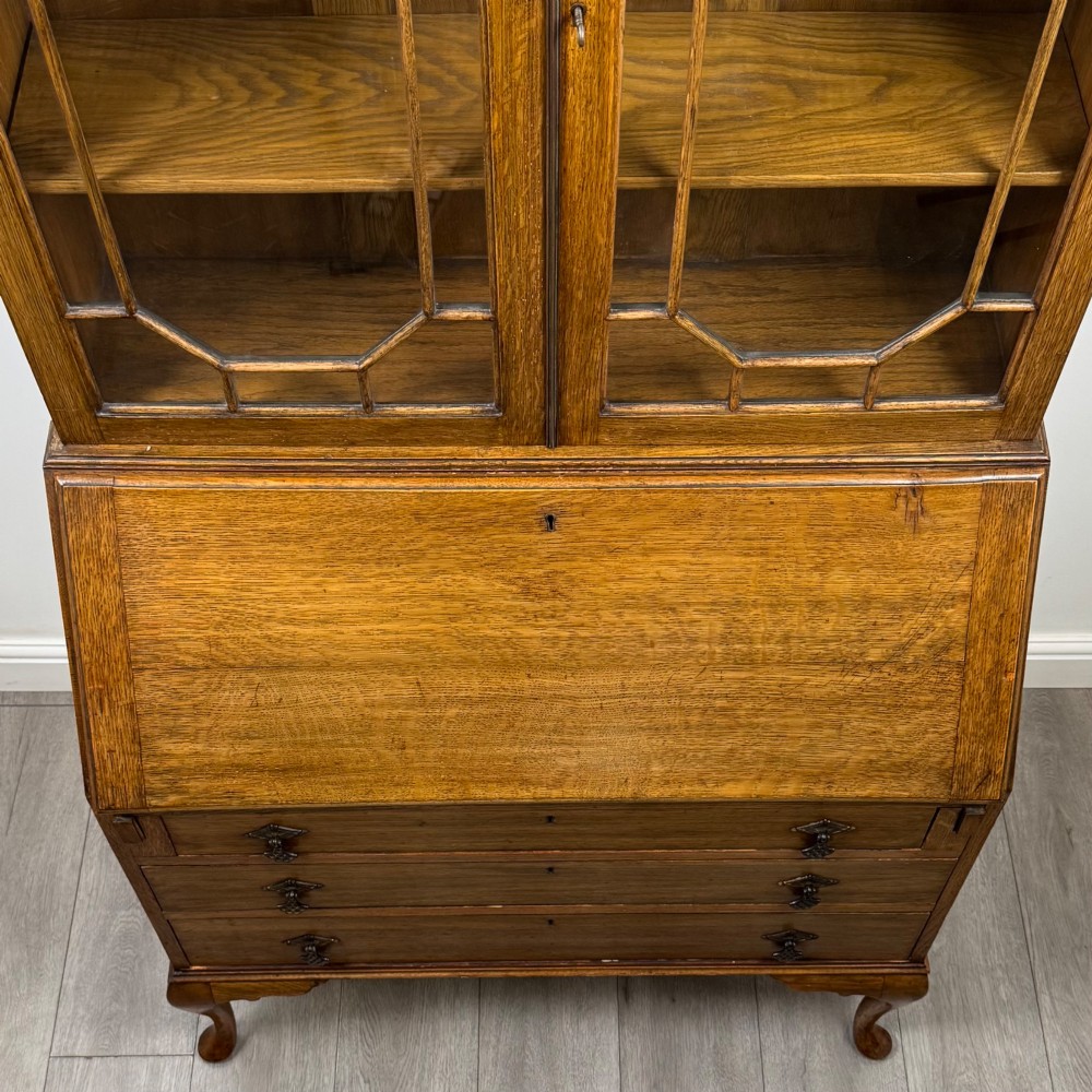 An Edwardian oak bureau bookcase with a two-door upper glazed display cabinet, a sloping drop-front desk, three wide drawers, and cabriole legs. View XI