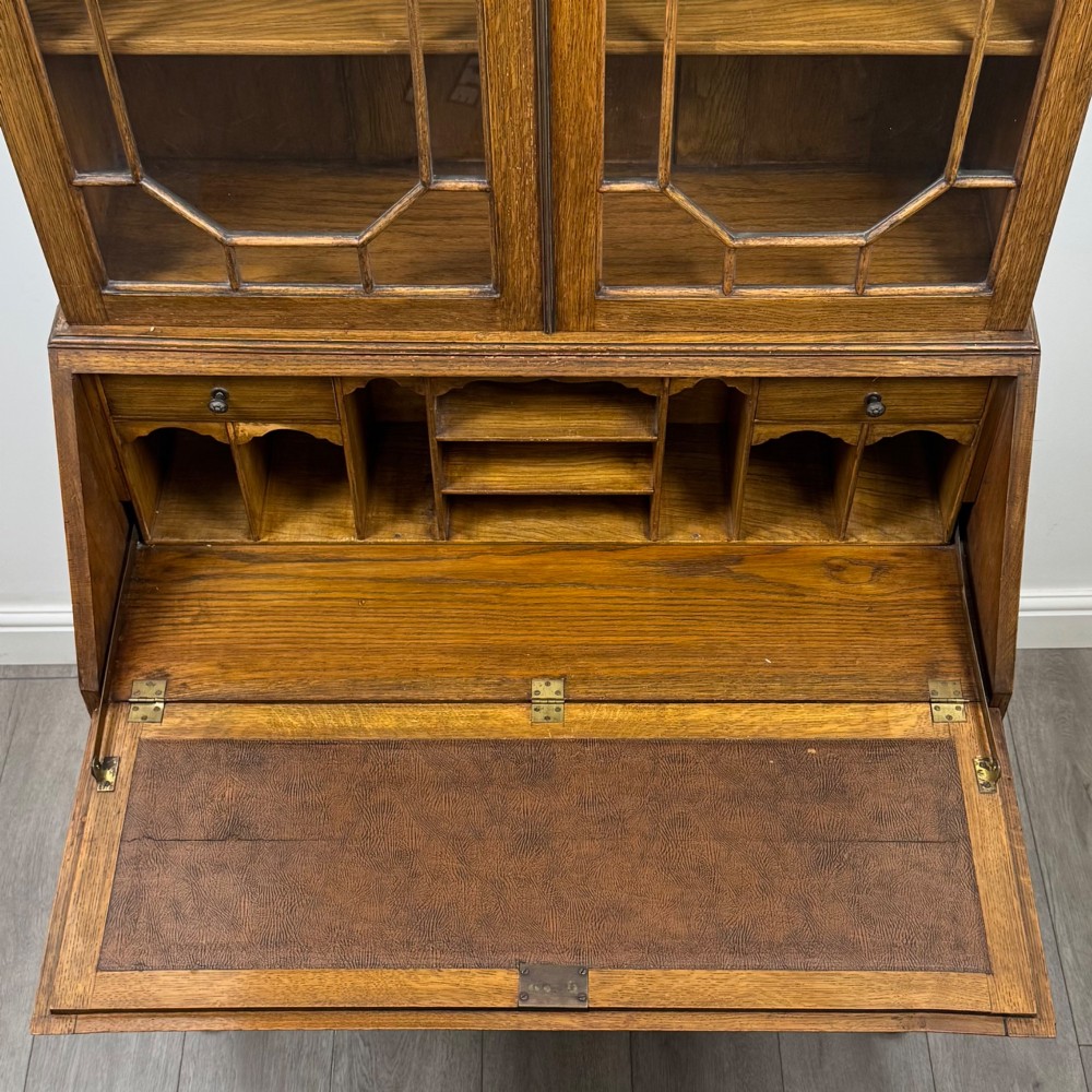 An Edwardian oak bureau bookcase with a two-door upper glazed display cabinet, a sloping drop-front desk, three wide drawers, and cabriole legs. View XII